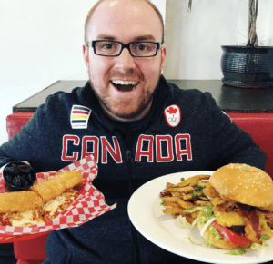 A man holding two burgers and smiling